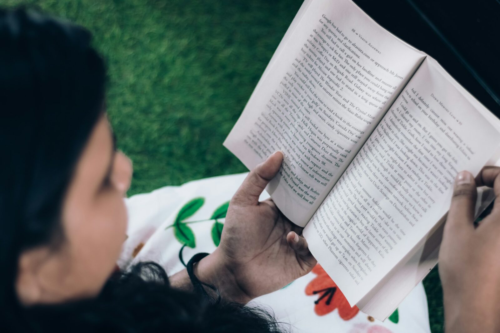 Woman reading a book while sitting on the grass