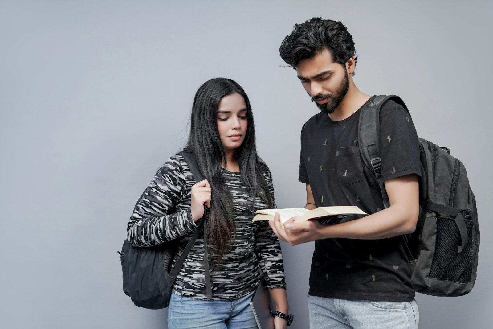 A young man and woman sitting side by side and studying from an open book