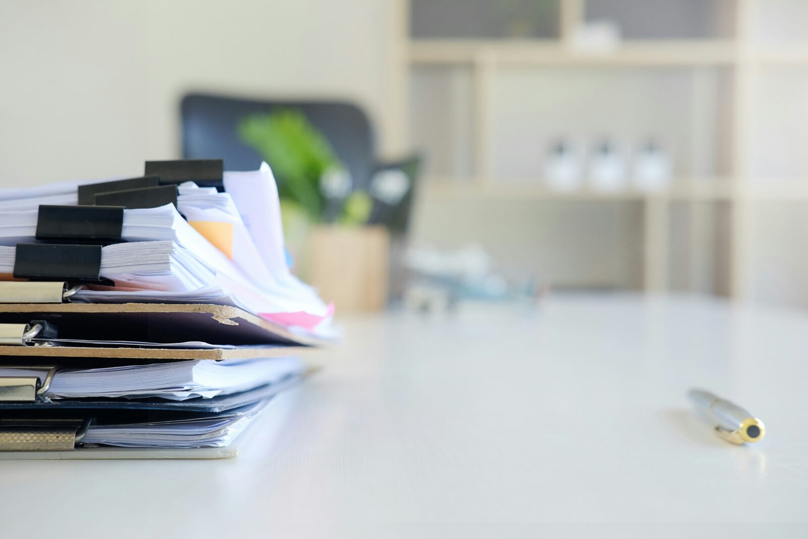 Maharashtra: Non-teaching Staffers Call for a Protest Tall stack of clipped paper files on a white office desk beside a pen
