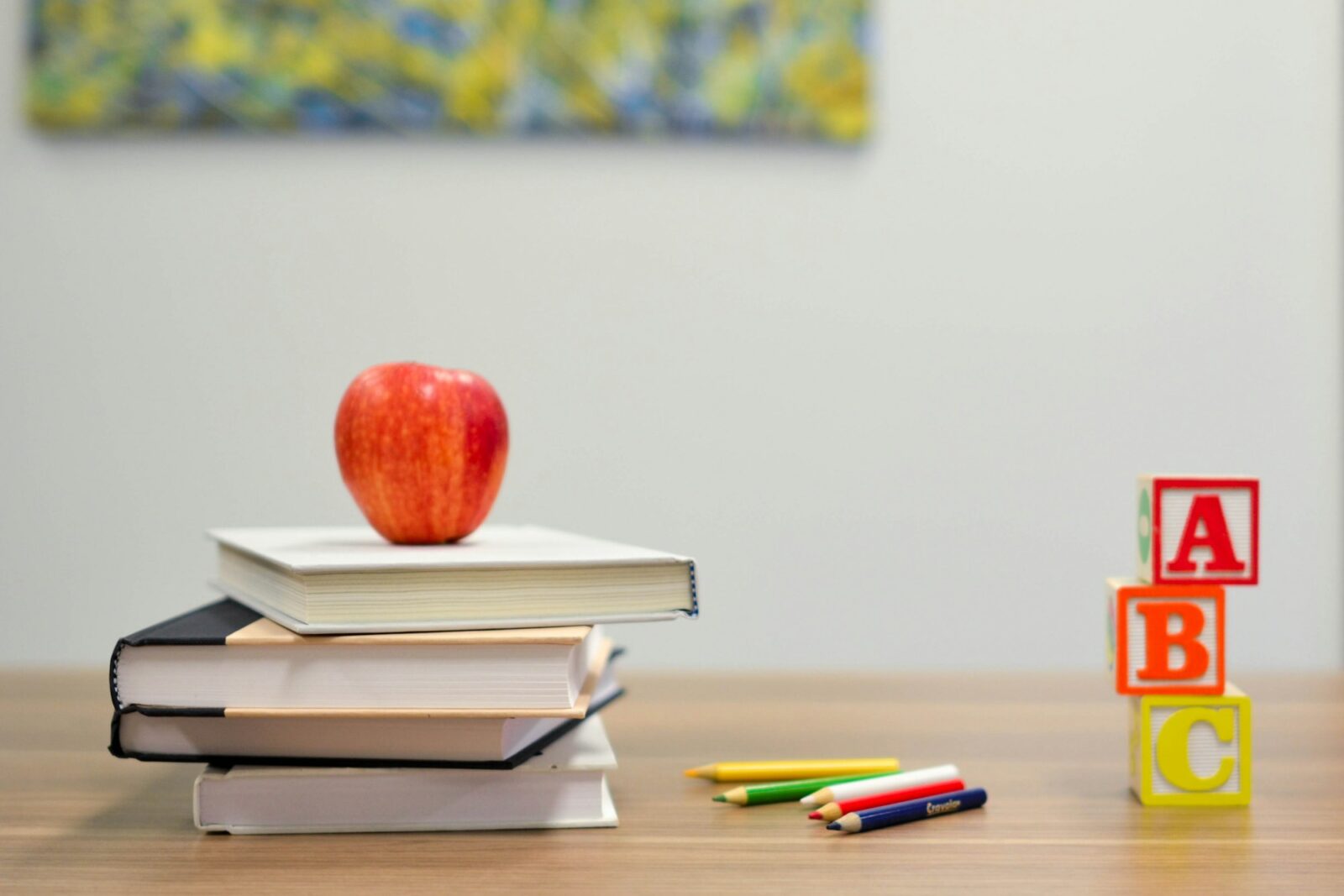 A red apple resting on top of a stack of four books