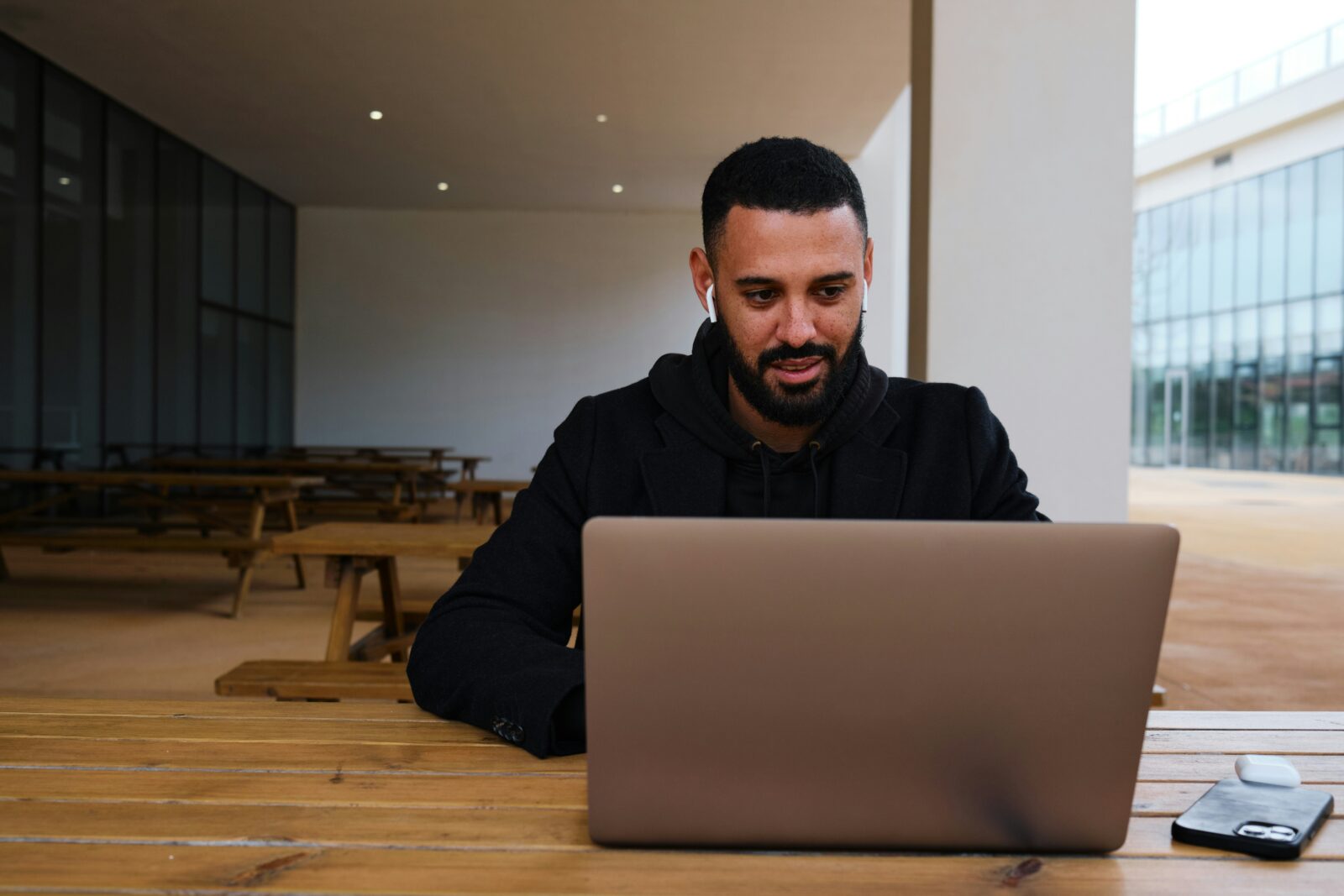 UP Chief Minister Yogi Adityanath introduces new online portal to help students Bearded man in a dark hoodie smiling at a laptop at an outdoor wooden table