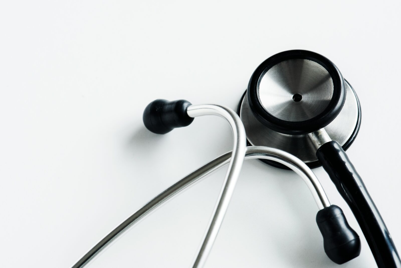 Close up of a stethoscope chest piece and tubing on a white surface