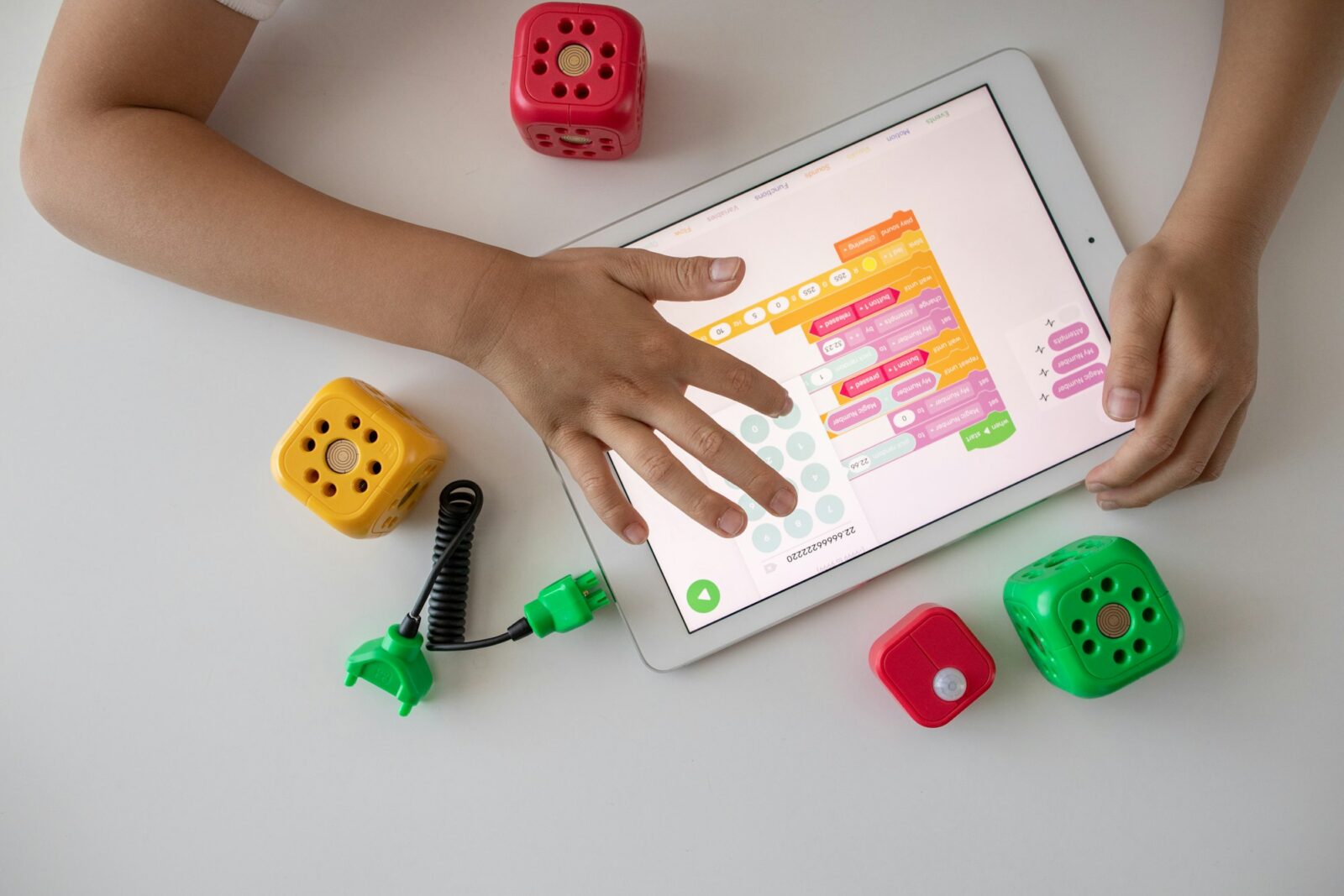 A child holding a white tablet on a white table during a learning activity