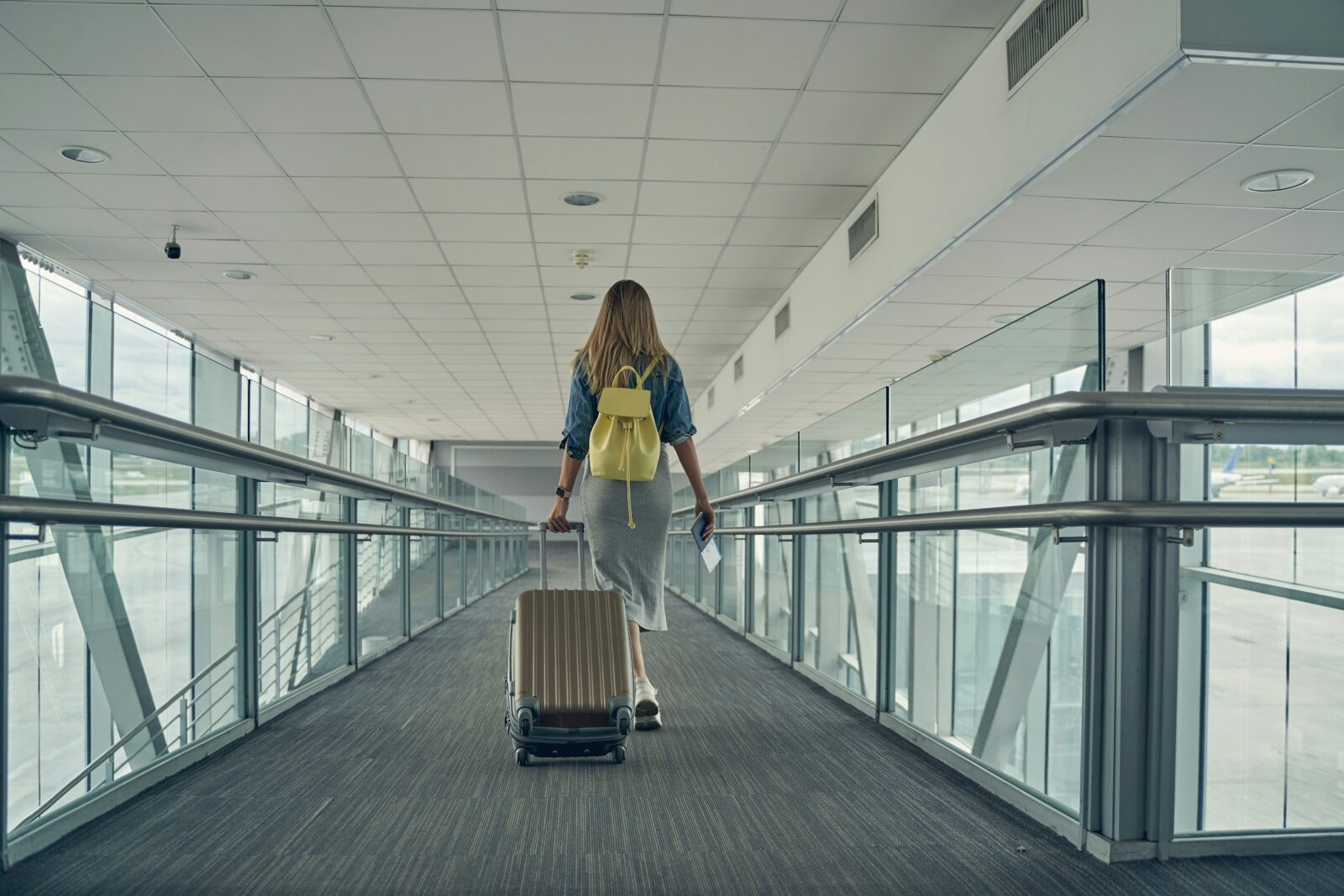 Nearly 2 lakh Indian students chose to pursue higher studies in US this 2019-20 academic year A woman with a yellow backpack wheeling a suitcase along an airport walkway, seen from behind