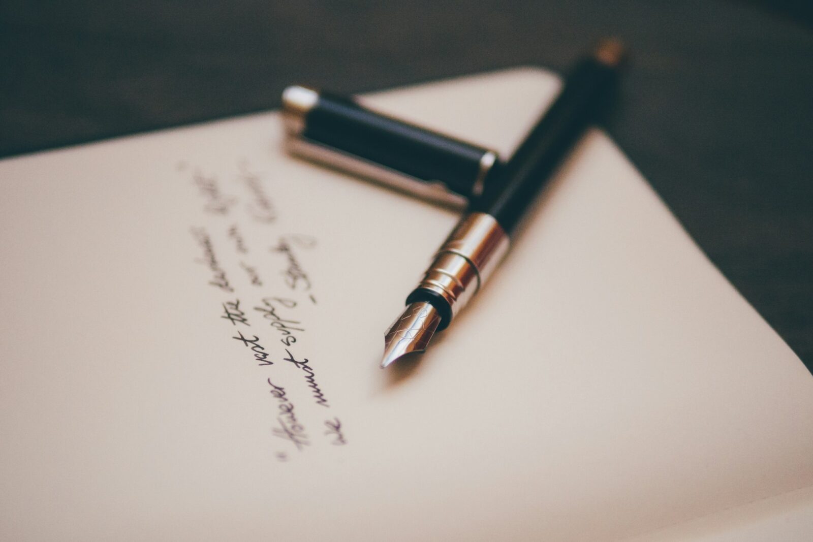 A black and silver fountain pen resting on sheets of writing paper
