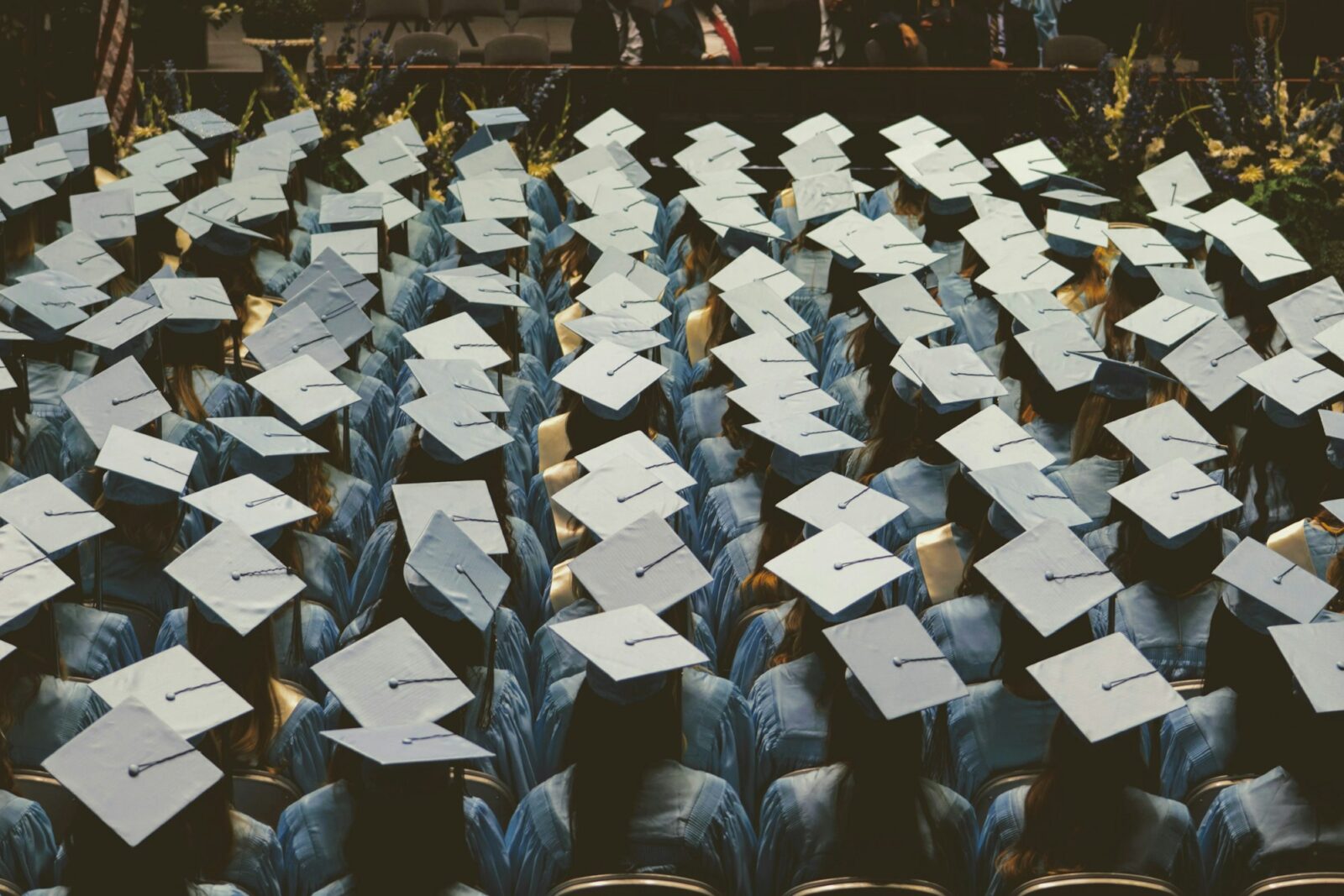 A large group of graduates in light blue gowns and caps at a ceremony