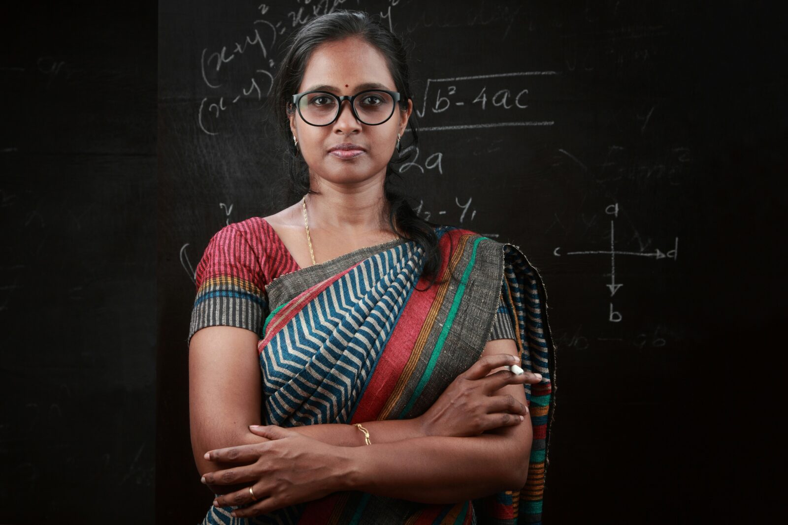 School Teachers To Be Vaccinated Till 5 Sept! A woman teacher standing in front of a blackboard in a classroom