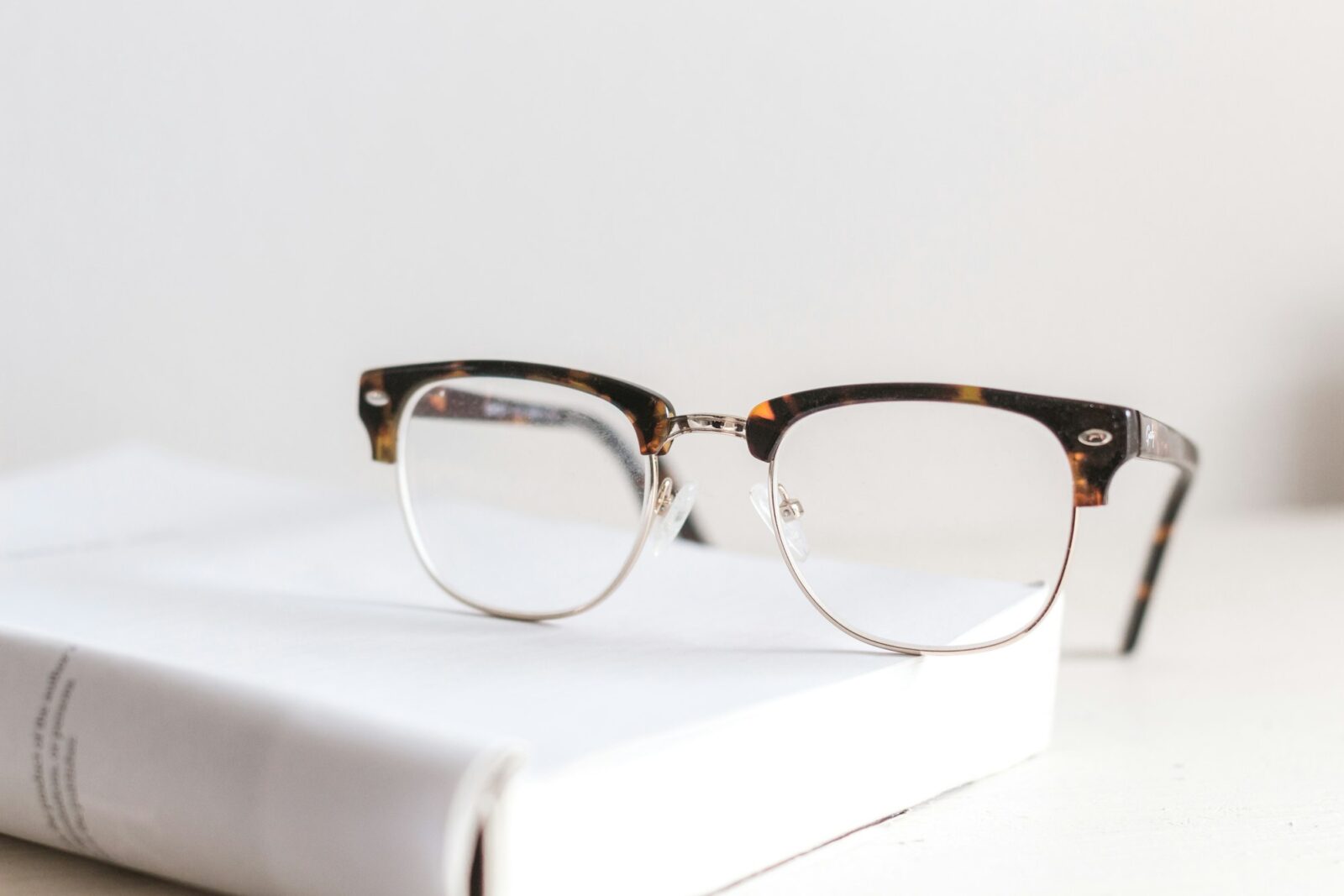 A pair of clear eyeglasses resting on an open book
