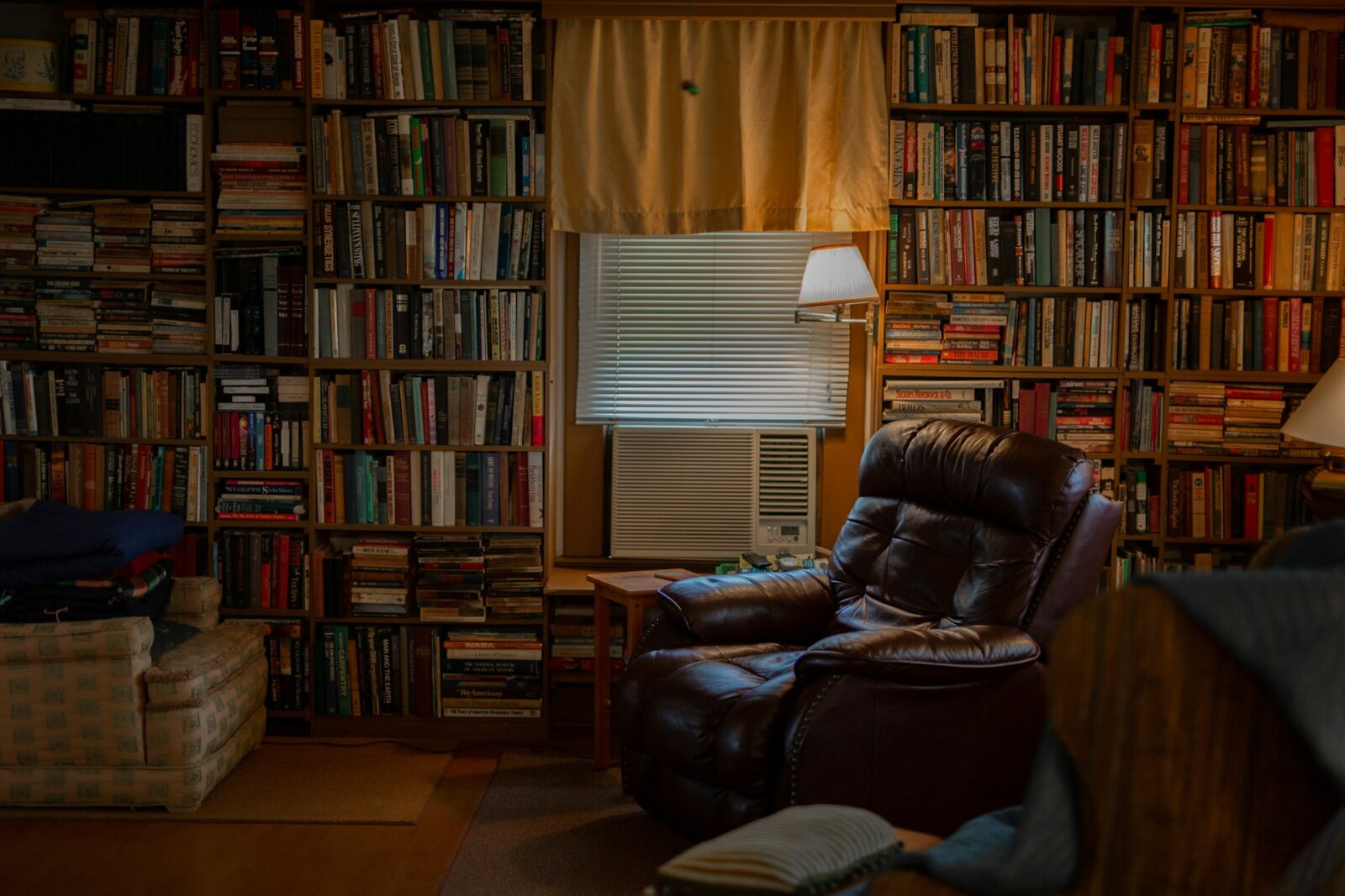 A brown leather recliner chair surrounded by shelves of books