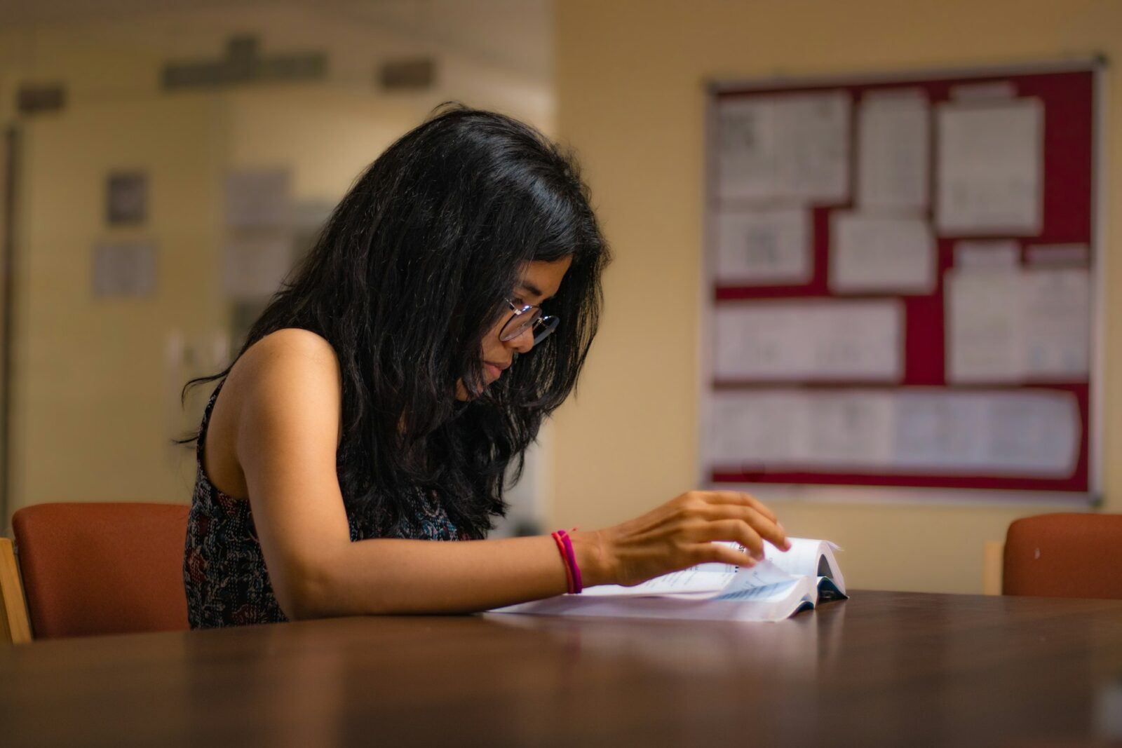 The government's role in girl's Education in India Young Indian woman studying an open book at a table in a college library