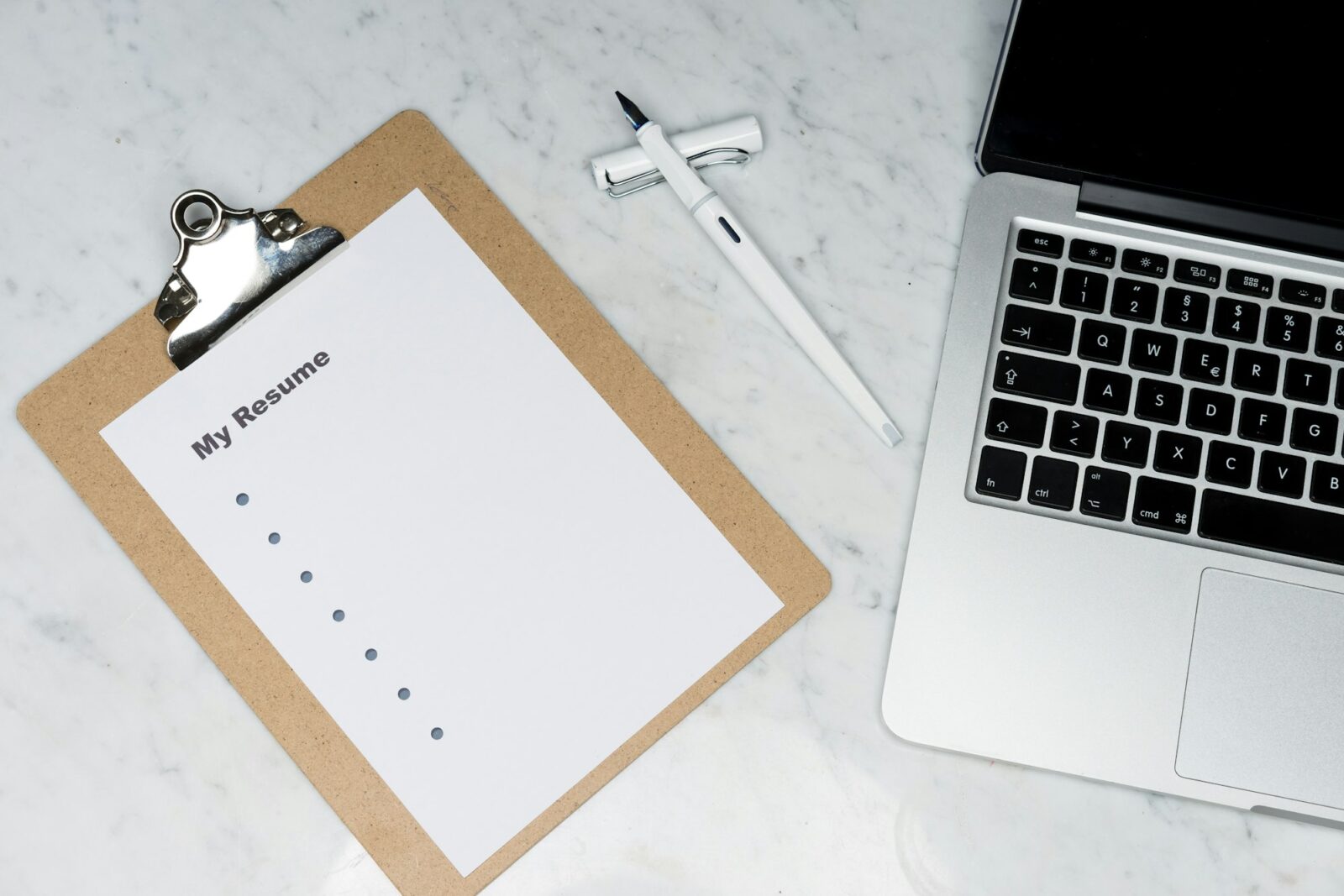 White sheet of paper beside a silver laptop on a desk