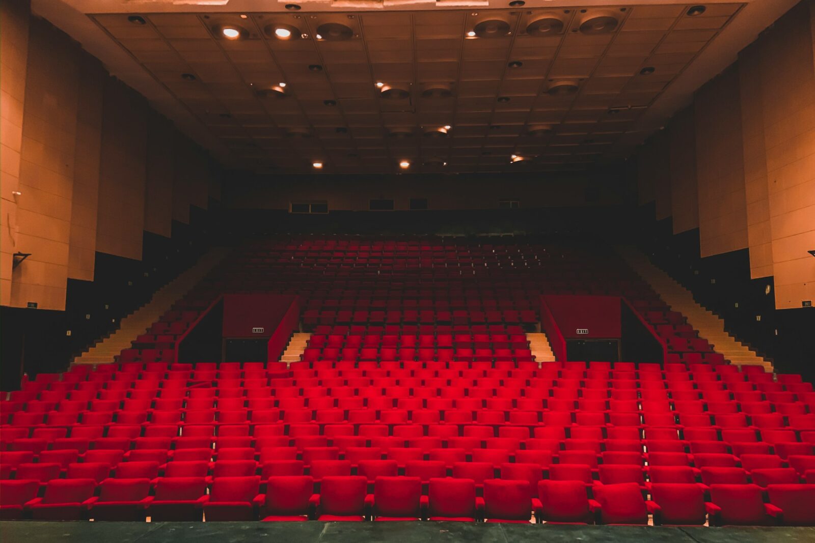 Rows of empty red seats in a large auditorium seen from the stage