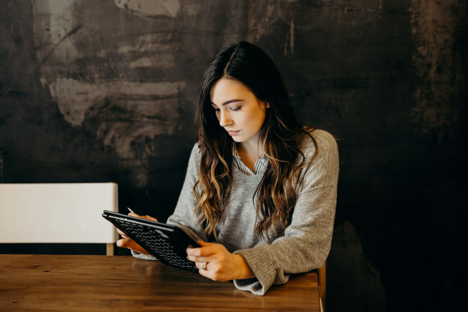 There are 8 Education Technology EdTech groups that all educators should be aware of Woman in a grey jumper using a tablet at a wooden table