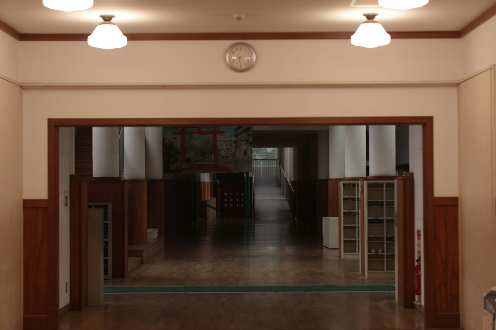Dimly lit school hallway with wooden panelling and white walls