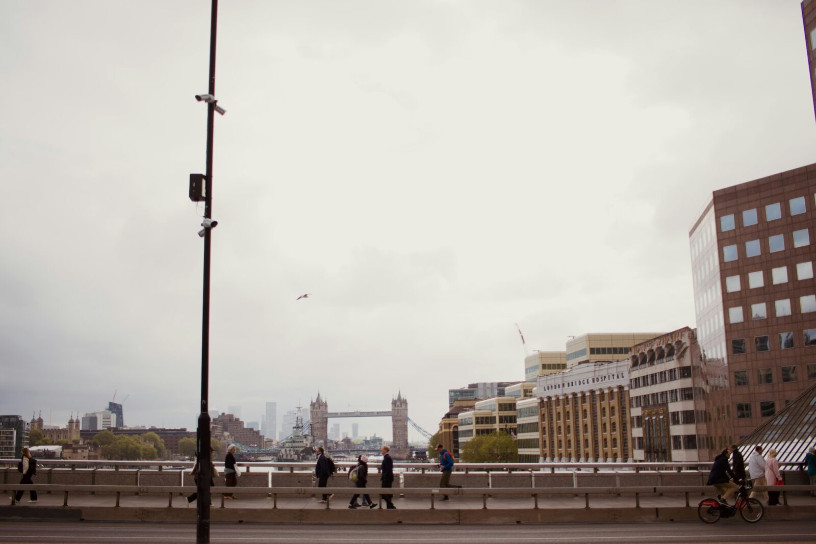 People walking across a bridge in London with Tower Bridge in the distance