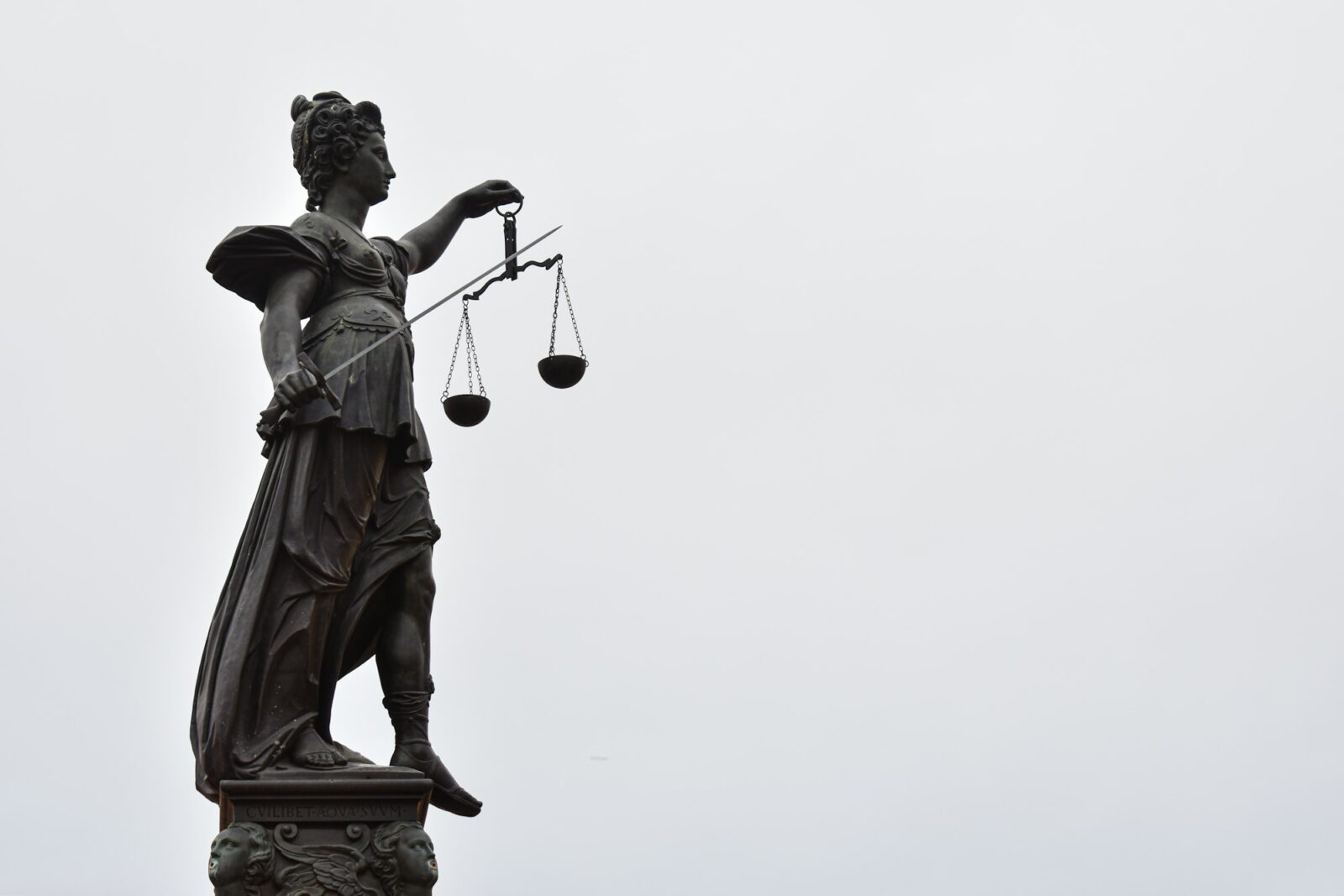 All clubs at Yeshiva University have been disbanded following a court order to accept an LGBTQ group Statue of Lady Justice holding a set of scales against an overcast sky