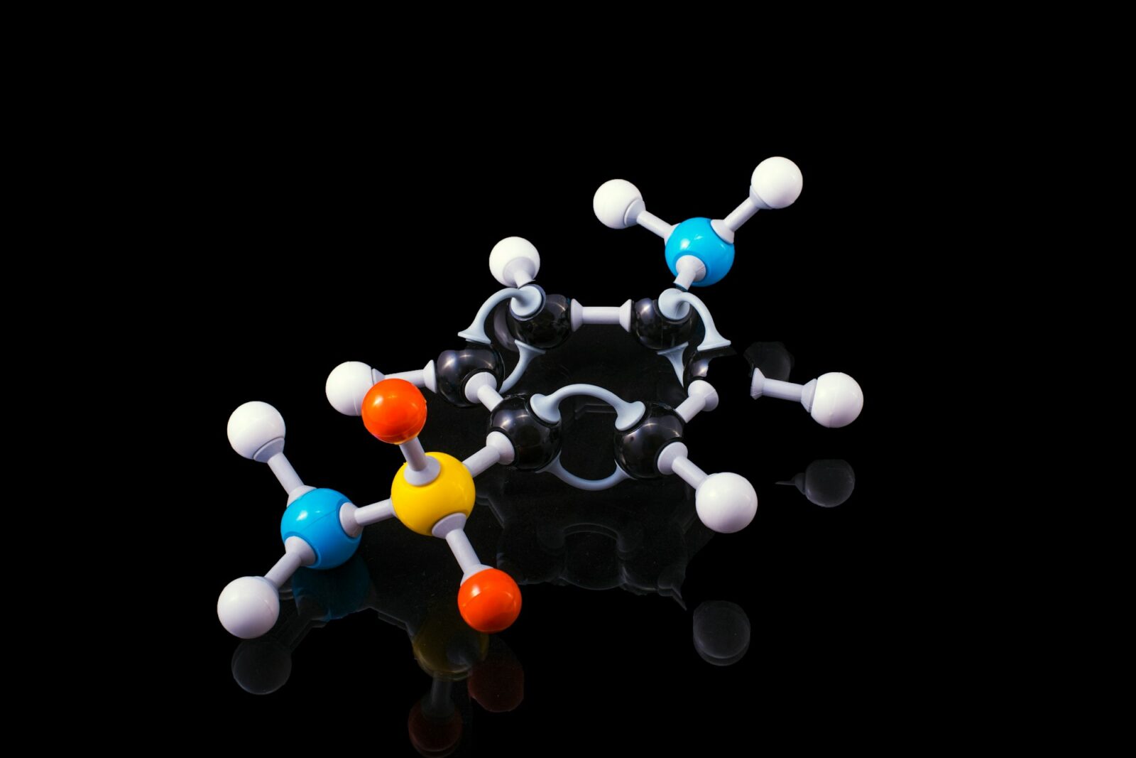 College Students and Professors Comment on the New Higher Education Landscape Following a Professor's Firing Molecular model with black, white, blue, orange and yellow spheres on a black surface