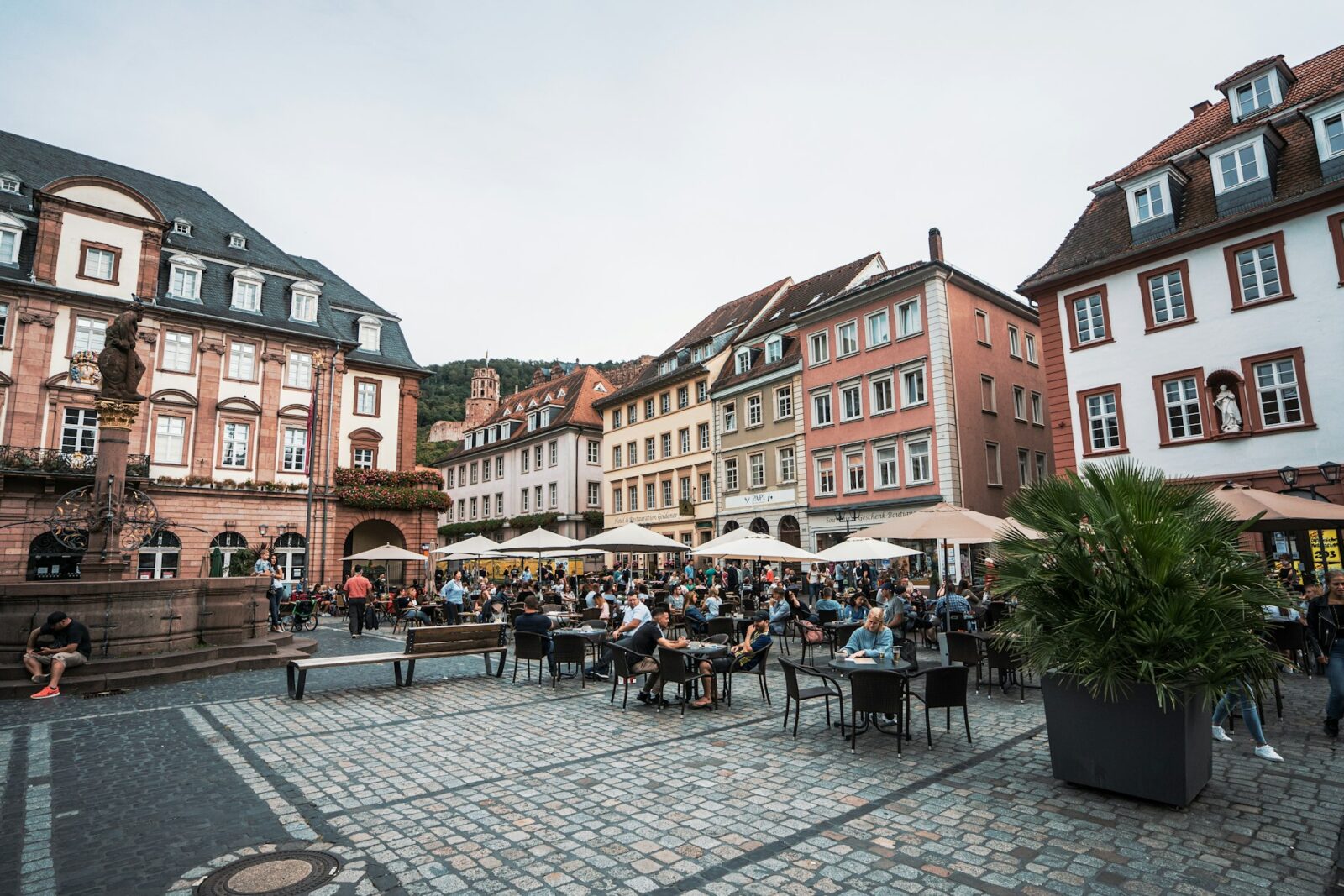 Medical PG (post graduation) in Germany People sitting at outdoor tables in a historic town square in Heidelberg, Germany