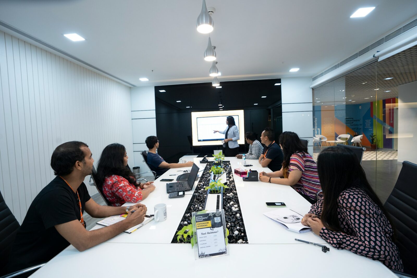 People seated at a table listening to a colleague presenting in a coworking office