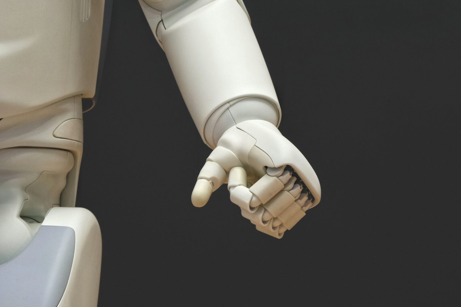 White humanoid robot holding out its hand against a dark background