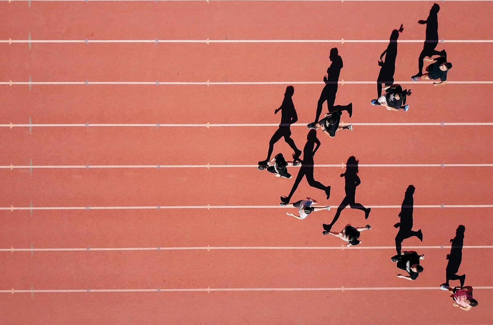 Use These 7 Powerful Study Skills Made From Sports to Win In School Aerial view of a group of runners on a red stadium track casting long shadows