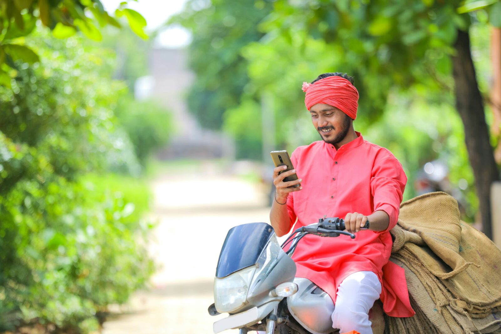 Boost in Adoption of EdTech in Developing Countries: Pros & Cons Young farmer in India sitting on a motorbike and using a smartphone
