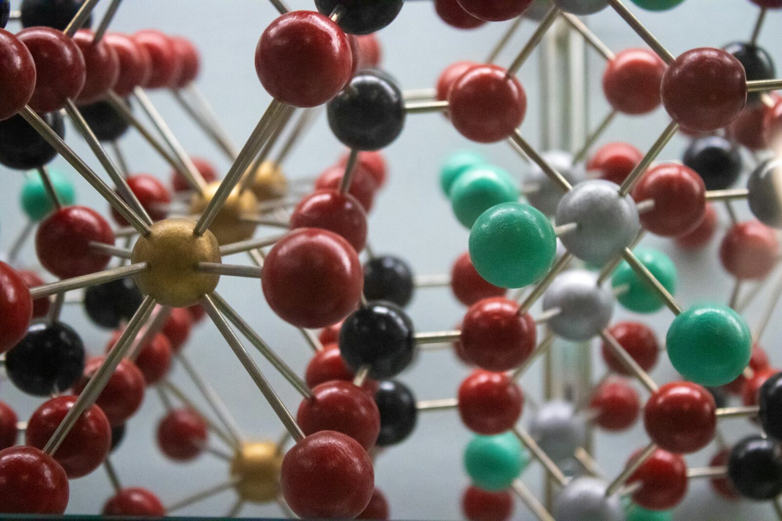 Close-up of a ball and stick molecular model with red, black, green and gold spheres