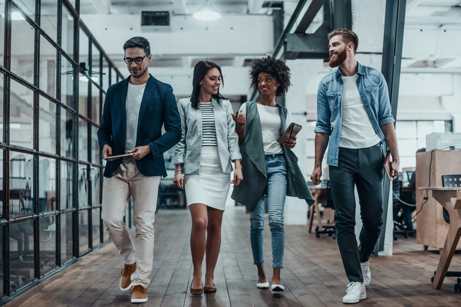 Edtech and the future of work: preparing students for the jobs of tomorrow Four young professionals in smart casual clothes talking as they walk through an open plan office