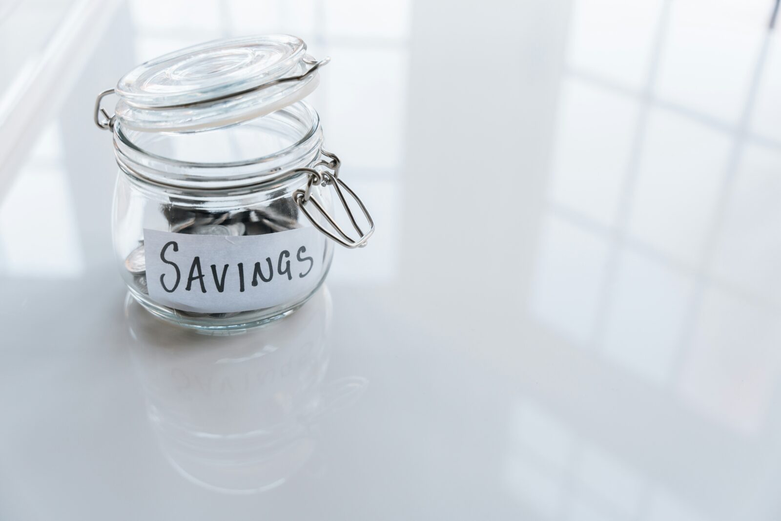 Studying abroad on a budget: tips and tricks for cost-effective travel and living Glass jar filled with coins on a table