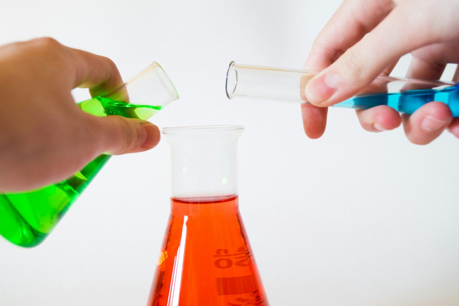 Person holding laboratory flasks during a science experiment