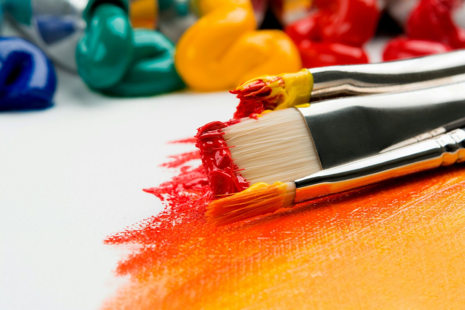Three paintbrushes with silver ferrules resting on white fabric