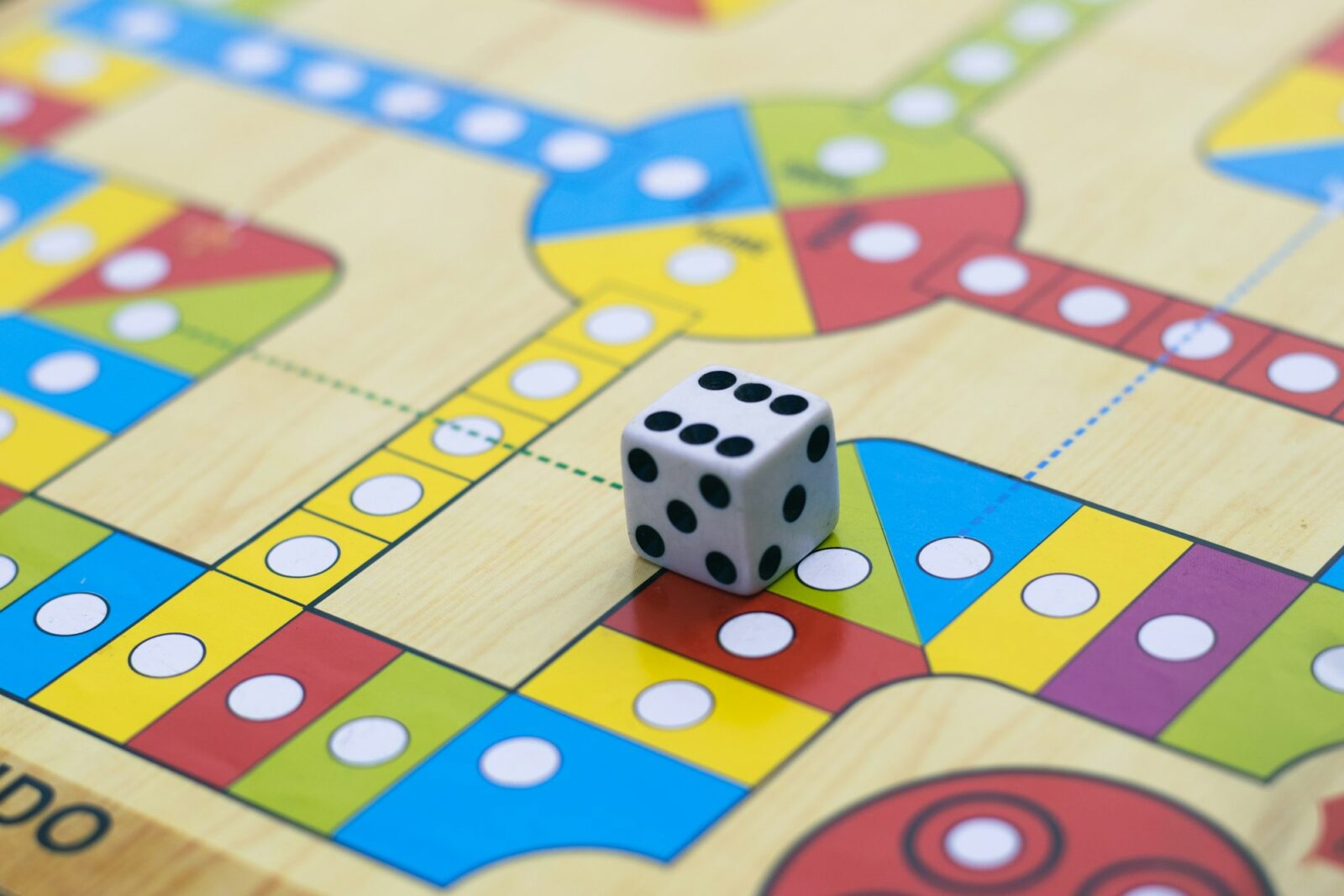 Close up of a dice resting on a colourful ludo board