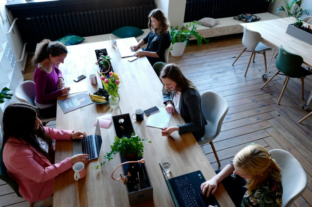 Founders working on laptops around a shared wooden table