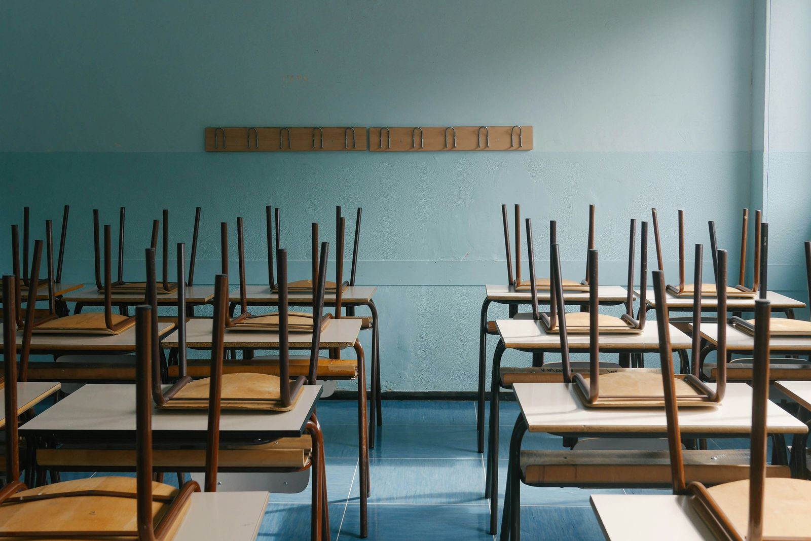Empty classroom with chairs stacked on wooden desks