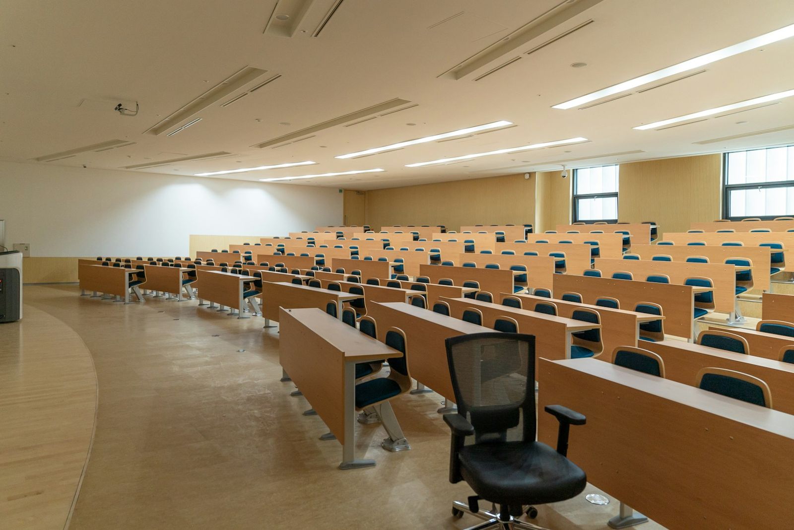 Rows of wooden desks in an empty lecture hall